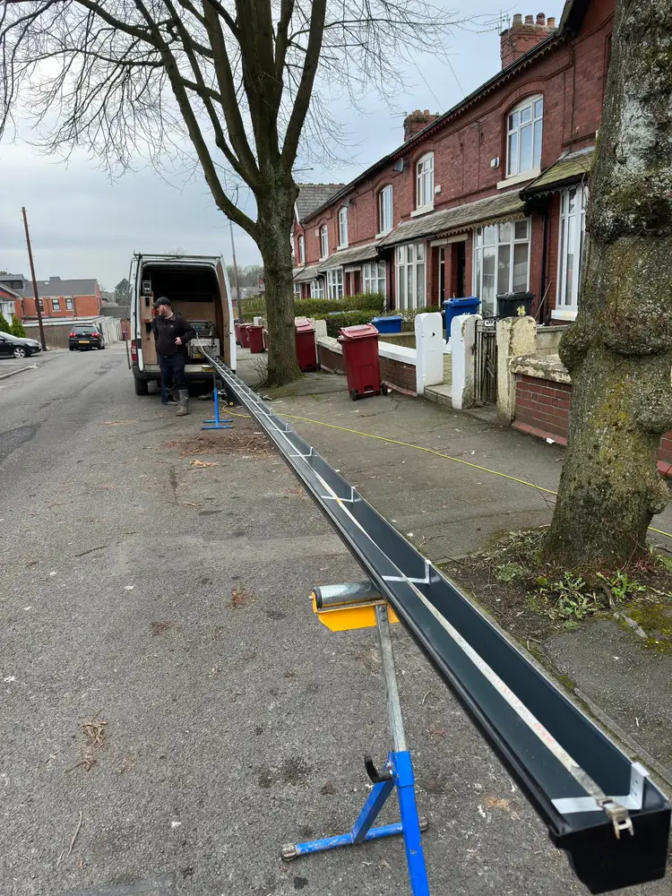 Gutterworx installer working on a long black aluminium gutter